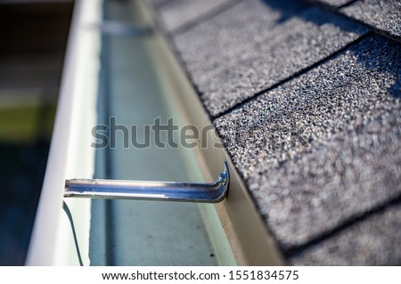 view inside roof gutter with clips and edge of shingles  Royalty-Free Stock Photo #1551834575