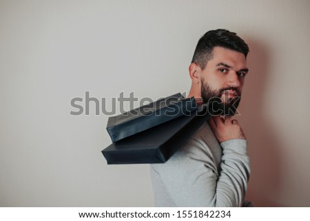 Black friday image with space for text. Bkack friday sale flat lay. Black friday bag. Bearded man with black paper bags on the white background. Man shopping.
