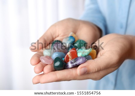 Woman holding pile of different gemstones indoors, closeup Royalty-Free Stock Photo #1551854756