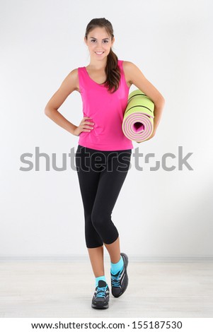 Beautiful young girl with gym mat at home