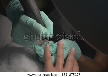 Woman hands receiving a manicure in beauty salon. Nail filing. Close up, selective focus.Female hands in the process of manicure, cutting of the cuticle, correction of the shape of the nail plate