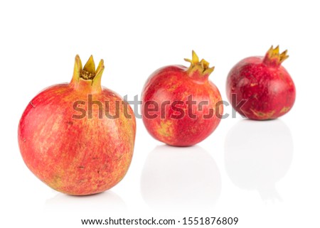 Group of three whole fresh red pomegranate placed diagonally isolated on white background