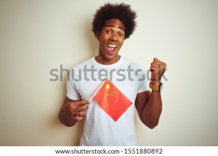 Young afro american man holding China Chinese flag standing over isolated white background screaming proud and celebrating victory and success very excited, cheering emotion