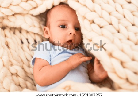 Adorable baby lying down over blanket on the sofa at home. Newborn relaxing and resting comfortable