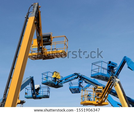 Several aerial working platforms of cherry picker against blue sky	 Royalty-Free Stock Photo #1551906347