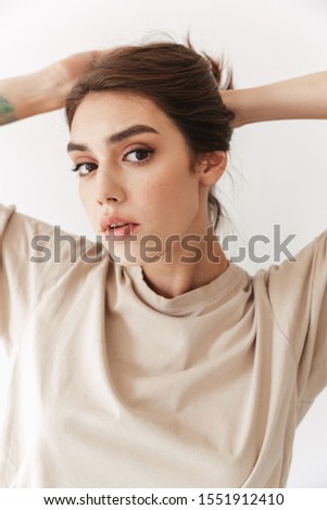 Photo of young beautiful woman posing indoors isolated over white wall background.