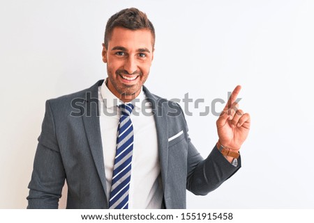 Young handsome business man wearing suit and tie over isolated background with a big smile on face, pointing with hand finger to the side looking at the camera.