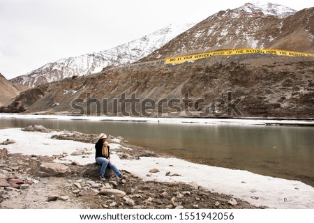 Travelers thai woman travel visit and posing portrait for take photo at view point of Confluence of the Indus and Zanskar Rivers while winter season at Leh Ladakh in Jammu and Kashmir, India