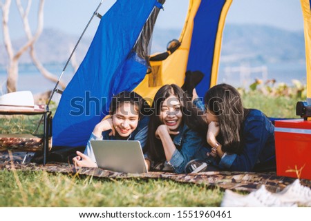 Lovely young tourists relax with rivers and mountains, pick up notebooks, see pictures, camping today, enjoy mountain climbing and holidays camping and tarvel concept.