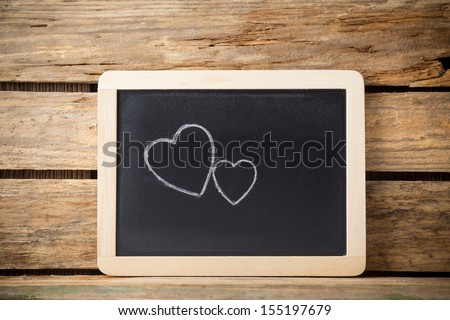 Blackboard on wooden background with heart from the cookie.