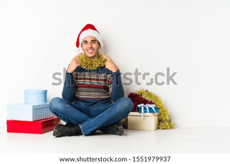 Young man on christmas day shocked and amazed holding a copy space between hands.