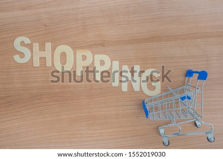 Shopping words with wood letters over wood background with shopping cart