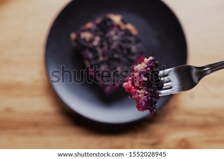 Baked oatmeal with blueberries served on a black plate with one piece bite, up on the fork above the plate