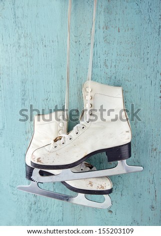 Pair of white women's ice skates on blue vintage wooden background - feminine winter sports concept