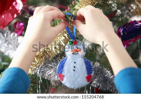 hang handmade xmas decoration on Christmas tree