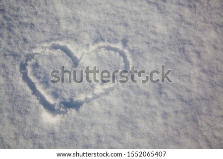 Symbol of the heart painted on the fresh white snow in winter season.