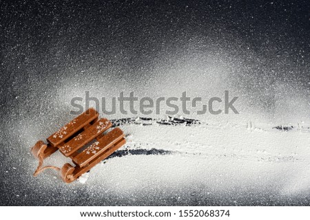 wooden sled on white snow on a black background, top view