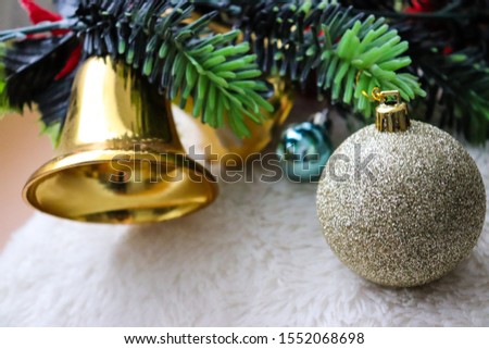 Christmas decorations close up. Sparkly christmas ornaments, christmas tree, gifts, bells, christmas lights, fuzzy white background. Festive holiday season. Red and gold decorations. 