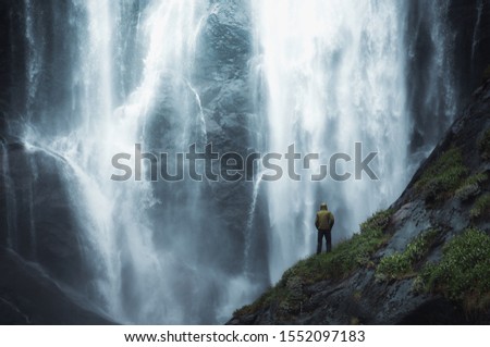 adventure man looking at waterfall in norway.  Royalty-Free Stock Photo #1552097183