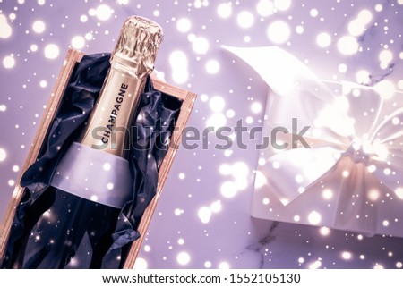 Celebration, drink and branding concept - Champagne bottle and gift box on purple holiday glitter, New Years, Christmas, Valentines Day, winter present and luxury product packaging for beverage brand