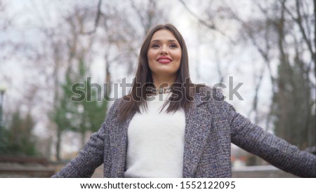 Happy Woman dancing on the street. Girl with beautiful smile. Cheerful, positive girl in a coat dancing on the street.