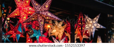 Festive lightning decorations, colorful star lanterns hanging on european Christmas market