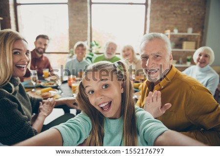 Video call from happy big family celebrate thanksgiving day october autumn event party small little girl kid make selfie mature grandfather say hi wave hand grandmother enjoy meal in house Royalty-Free Stock Photo #1552176797