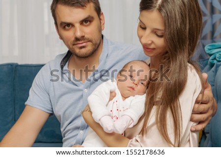 Smiling mother and father holding their newborn baby daughter at modern home