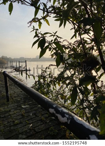 Misty November morning on the Thames path Hammersmith west London calm and atmospheric warmer river scenes with bridge snd cityscape skyline