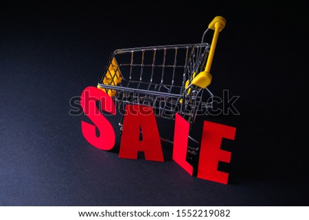 Black friday sale in red letters on a black background. Minimalism style. Shopping cart. Sale, discounts, shopaholism concept.