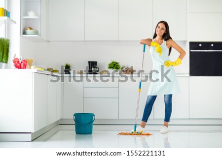 Full length photo of positive cheerful housewife wearing yellow rubber gloves enjoy washing floor hold mop feel content wearing denim jeans casual good looking clothing in house indoors