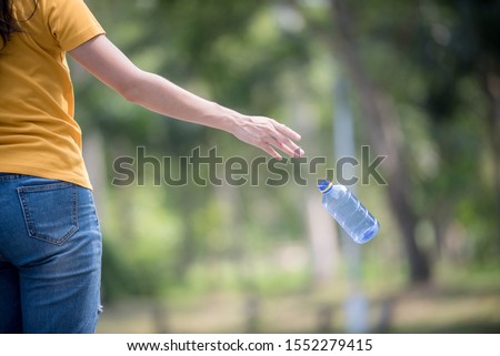 Hand throwing away plastic bottle in nature. Environmental damage by plastic waste.Environmental conservation Royalty-Free Stock Photo #1552279415