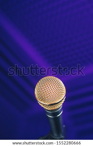 golden microphone on stand, purple background with acoustic foam in studio