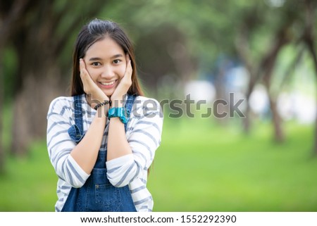 Smiling beautiful Asian girl at tree on park in summer for relax time