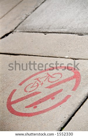 no skateboarding or bicycling on sidewalk - painted symbol on sidewalk. limited dof with copyspace and focus on skateboard