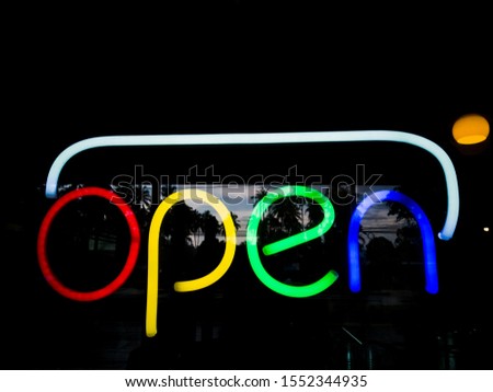 OPEN, neon sign  trough window, reflected view and orange light in background, welcome customer concept. 