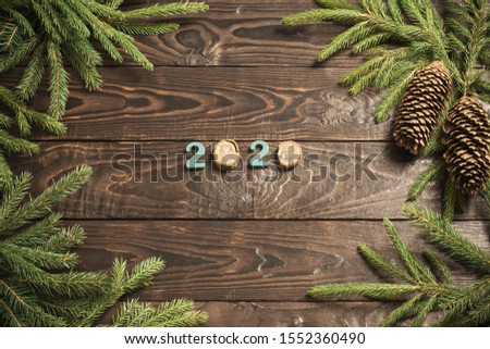 New Year composition, 2020 simbols and fir branches with cones on old wooden background