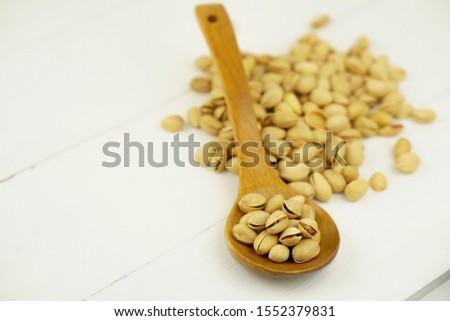 Close up Pistachio on white wooden background and spoon. Selective focus. Copy Space