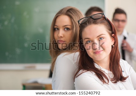 Two posing schoolgirls smiling in a classroom