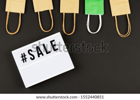 colored packaging bags, lightbox with text sale on black background Top view Flat lay . sesonal sale, retail, shopping concept