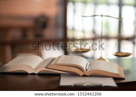 law books and scales of justice on desk in library of law firm. jurisprudence legal education concept. Royalty-Free Stock Photo #1552461206