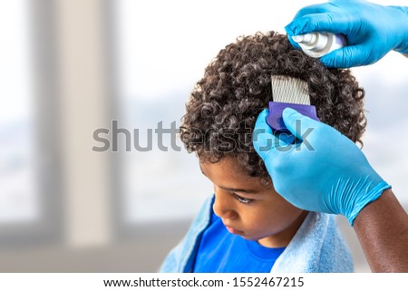Mother checking childs head for lice with a comb