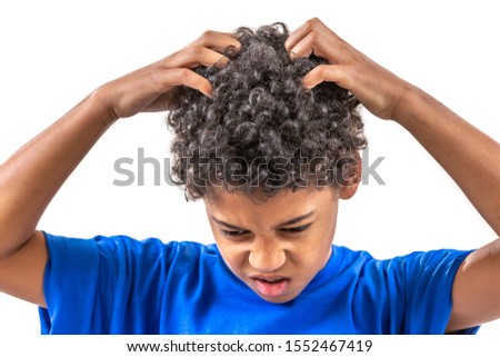 Smiling young boy scratching hair for head lice or allergies.