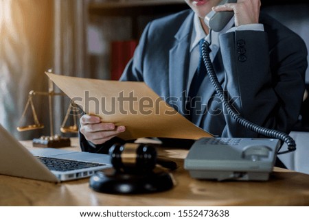 Justice and law concept.Male judge in a courtroom with the gavel, working with, computer and docking keyboard, eyeglasses, on table in morning light.