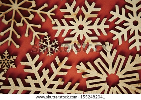 Christmas red background with wooden rustic snowflakes.Handmade crafts flat lay on vibrant color backdrop.Happy New Year wallpaper with hand crafted decorations