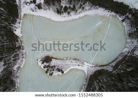 Aerial view of the lake in the shape of a heart and forest in winter. Photo of the northern nature from the drone.