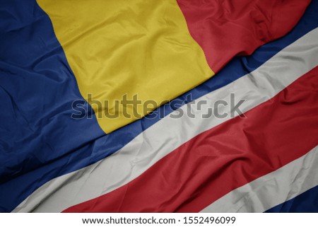 waving colorful flag of costa rica and national flag of romania. macro