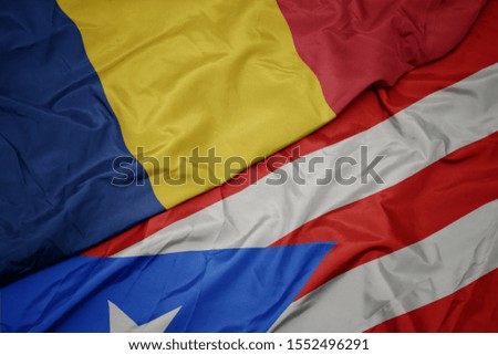 waving colorful flag of puerto rico and national flag of romania. macro