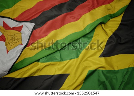 waving colorful flag of jamaica and national flag of zimbabwe. macro
