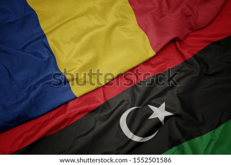 waving colorful flag of libya and national flag of romania. macro